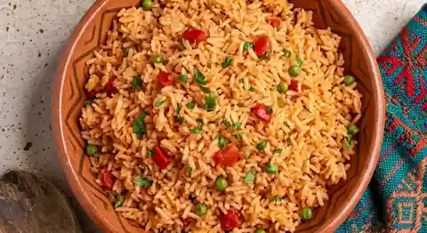 Arroz rojo mexicano en un tazón de talavera azul con chícharos, zanahoria, elote, cilantro y queso fresco